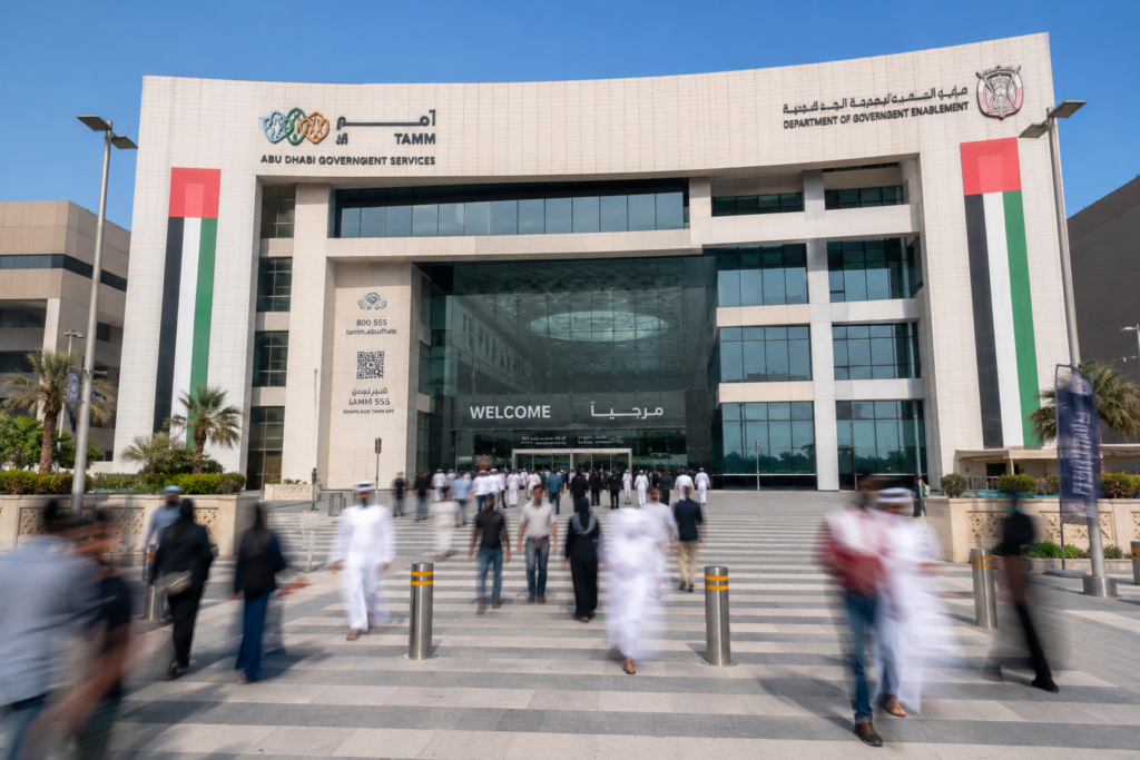 UAE government office building in Abu Dhabi with visitors, UAE flags, and official signage in a wide cityscape view.